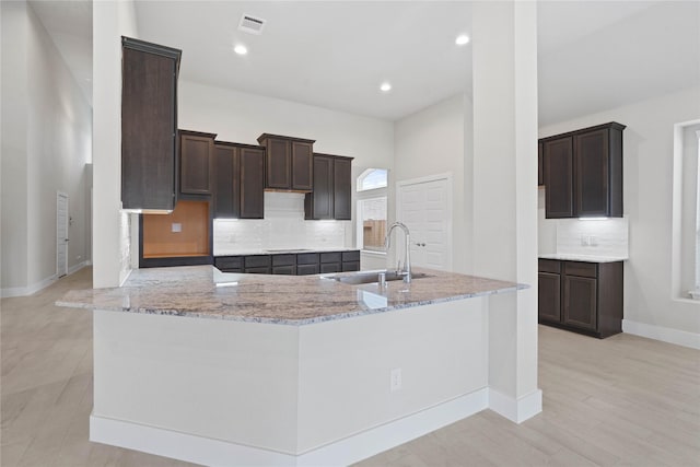 23415 Persimmon Creek Ln, Katy, TX 77493 - kitchen featuring light stone countertops, dark brown cabinetry, backsplash, recessed lighting, and light wood-style flooring