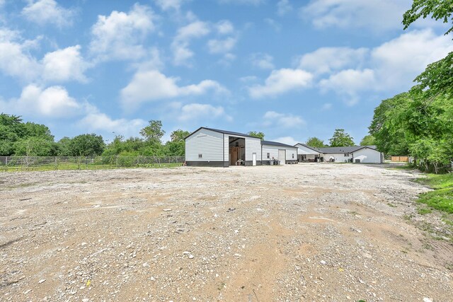 view of yard featuring fence, dirt driveway, and an outdoor structure