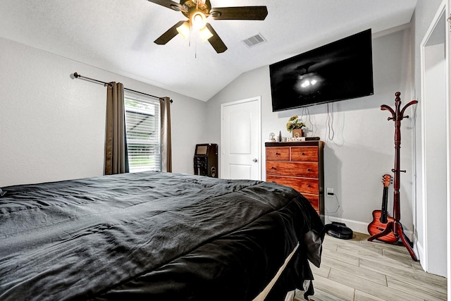 bedroom featuring light wood finished floors, a ceiling fan, baseboards, vaulted ceiling, and visible vents