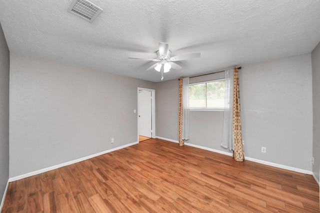 spare room featuring visible vents, baseboards, ceiling fan, and wood finished floors