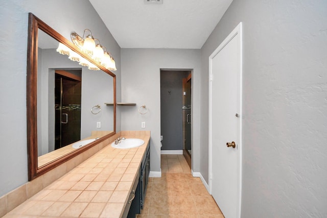 bathroom with vanity, baseboards, and tile patterned floors