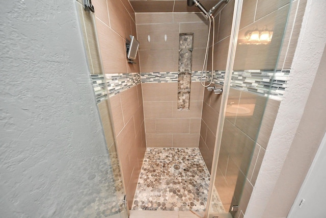 bathroom with a textured wall and a stall shower