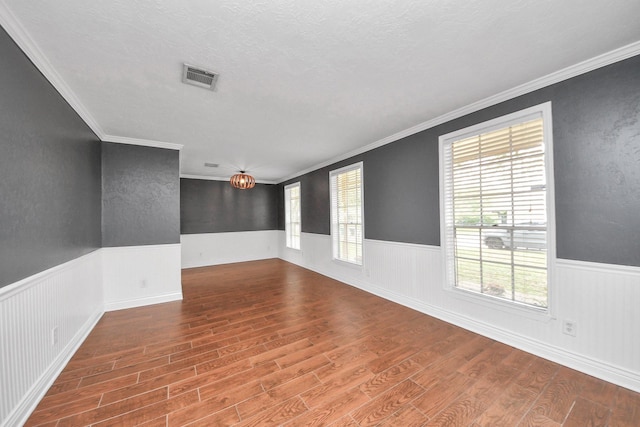 spare room featuring visible vents, wood finished floors, and a healthy amount of sunlight