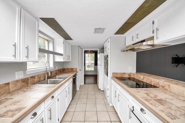 kitchen with visible vents, stainless steel dishwasher, a sink, white cabinets, and black electric stovetop