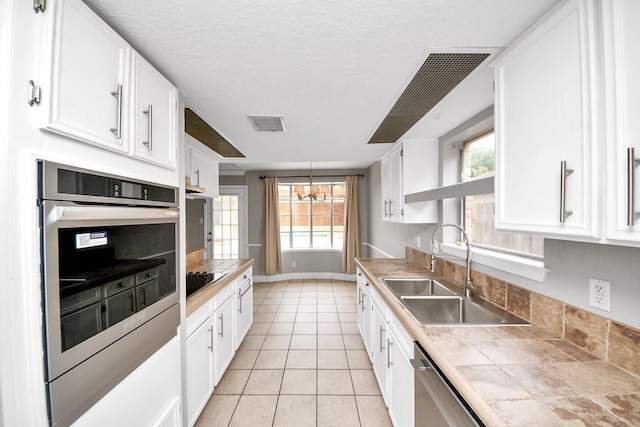kitchen featuring a sink, appliances with stainless steel finishes, white cabinets, and tile counters
