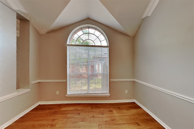 unfurnished room with baseboards, vaulted ceiling, and wood finished floors
