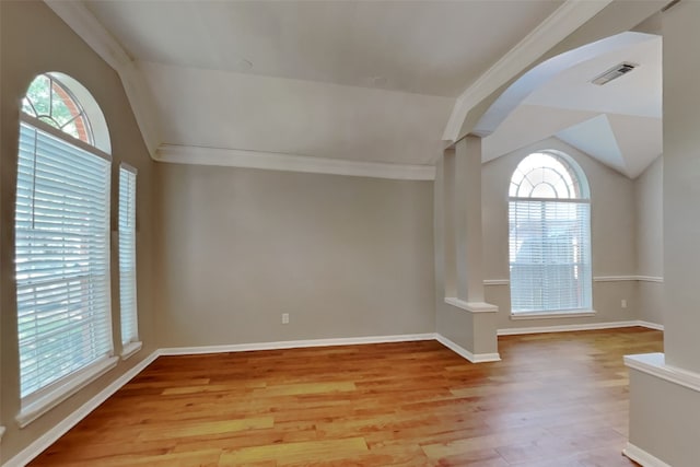 empty room featuring baseboards, ornamental molding, light wood-type flooring, and lofted ceiling