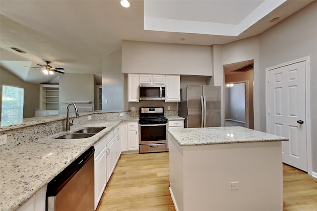 kitchen with light wood-type flooring, a center island, white cabinets, a sink, and appliances with stainless steel finishes