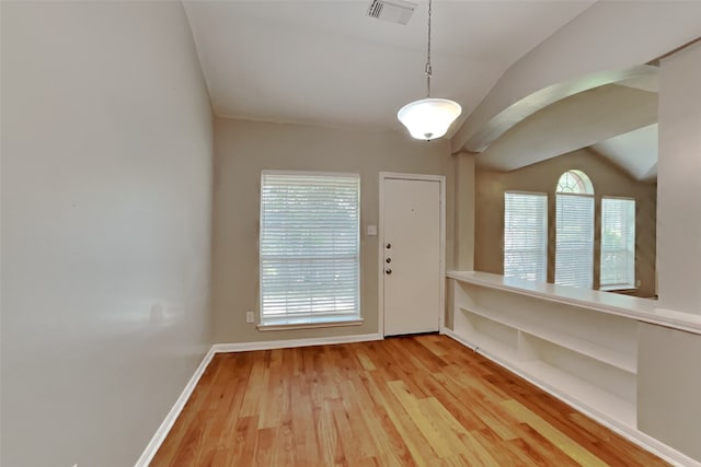 interior space featuring baseboards, lofted ceiling, wood finished floors, and visible vents