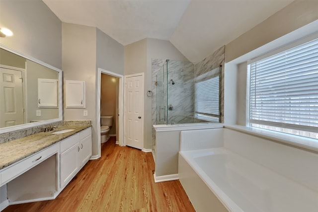bathroom featuring a garden tub, wood finished floors, lofted ceiling, toilet, and a stall shower