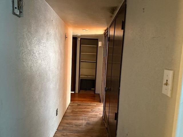 hallway with a textured wall and dark wood finished floors