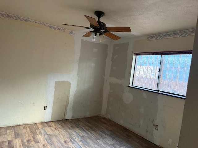empty room featuring a textured ceiling, ceiling fan, and wood finished floors