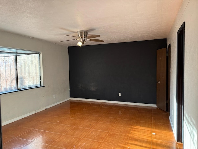 empty room with a ceiling fan, a textured ceiling, and baseboards