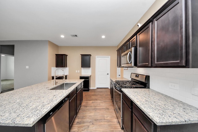 22619 Goose Pasture Ln, Spring, TX 77373 - kitchen featuring appliances with stainless steel finishes, light wood-type flooring, light stone counters, tasteful backsplash, and recessed lighting