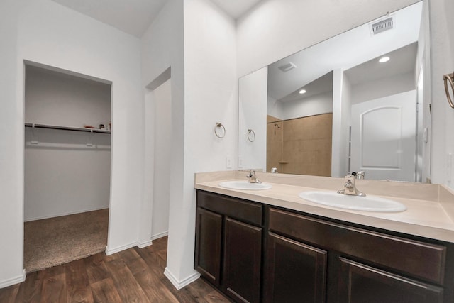 22619 Goose Pasture Ln, Spring, TX 77373 - full bathroom with double vanity, tiled shower, a spacious closet, and wood finished floors