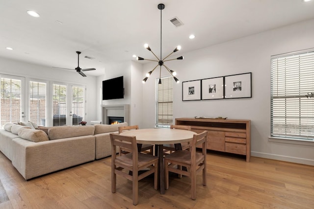dining room with a glass covered fireplace, recessed lighting, light wood-type flooring, and visible vents