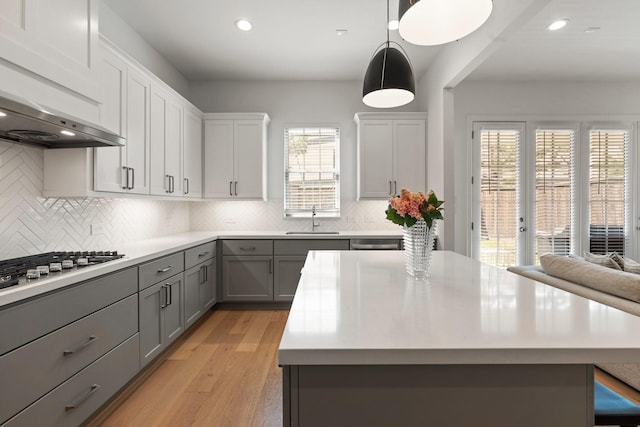 kitchen featuring a sink, gray cabinets, decorative backsplash, and light countertops