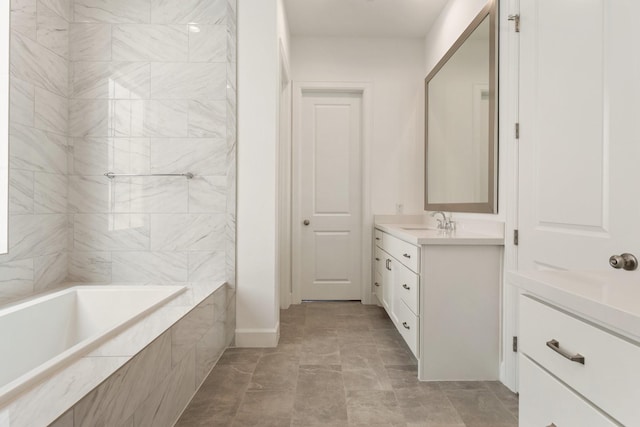 bathroom with vanity, baseboards, and tiled bath