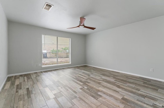 spare room with a ceiling fan, baseboards, visible vents, and wood finished floors