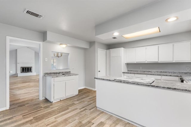 kitchen with white cabinetry, light stone countertops, and visible vents