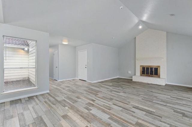 unfurnished living room with light wood-style floors, baseboards, a fireplace, and lofted ceiling