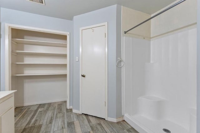 full bathroom with baseboards, visible vents, a shower stall, and wood finished floors