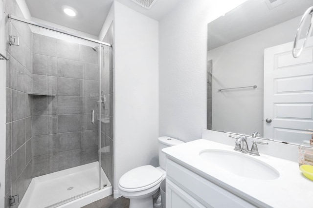 bathroom with vanity, a stall shower, toilet, and visible vents