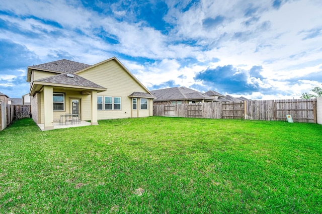 back of property featuring a patio, a fenced backyard, a lawn, and a shingled roof
