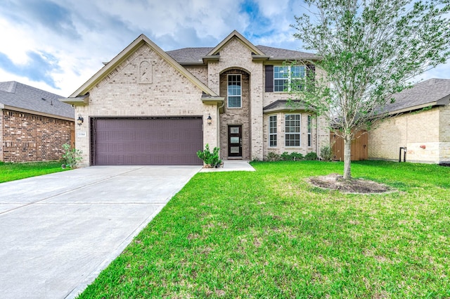 french country style house featuring a garage, concrete driveway, brick siding, and a front yard