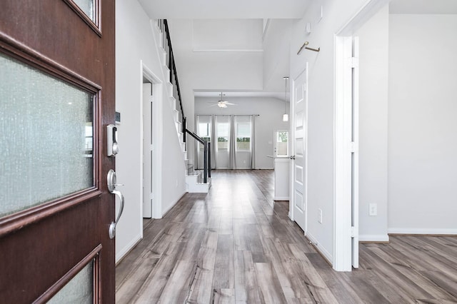 entryway featuring baseboards, ceiling fan, wood finished floors, and stairway