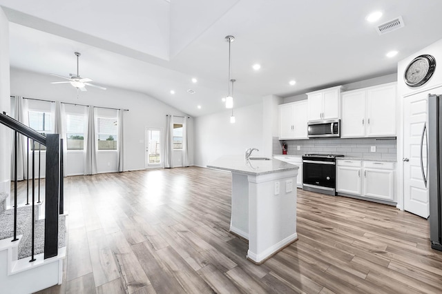 kitchen with visible vents, appliances with stainless steel finishes, vaulted ceiling, light wood-type flooring, and recessed lighting