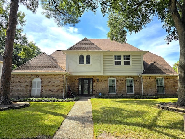 view of front of house featuring brick siding, french doors, and a front lawn