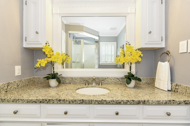 full bath featuring vanity, ornamental molding, and a shower with door