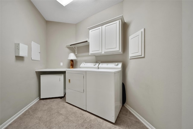 laundry area featuring light tile patterned floors, baseboards, cabinet space, and washer and clothes dryer