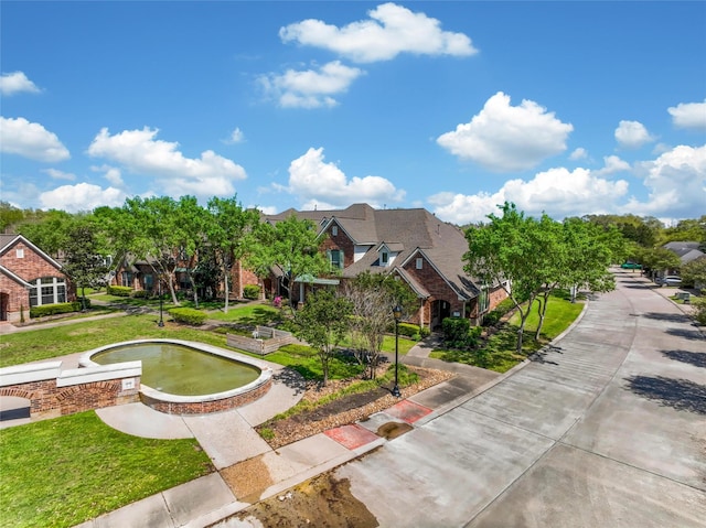 view of community featuring a lawn and curved driveway