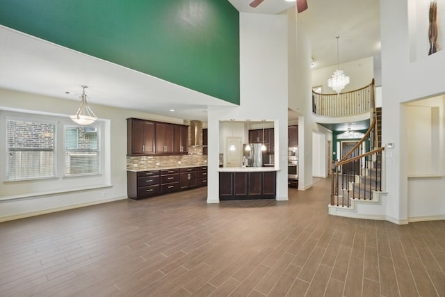 23 Castello Ln, Missouri City, TX 77459 - unfurnished living room with a high ceiling, dark wood finished floors, ceiling fan with notable chandelier, stairs, and baseboards