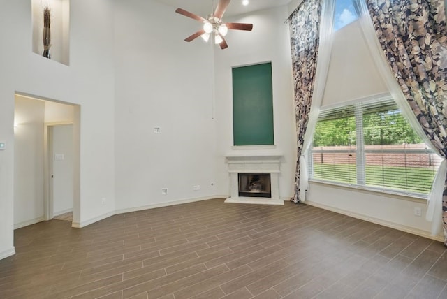 23 Castello Ln, Missouri City, TX 77459 - unfurnished living room featuring a ceiling fan, baseboards, a glass covered fireplace, and a towering ceiling