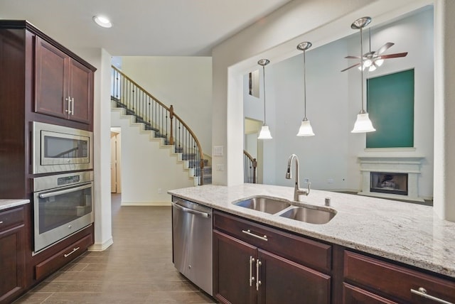 23 Castello Ln, Missouri City, TX 77459 - kitchen featuring a ceiling fan, light stone countertops, dark wood-type flooring, a sink, and appliances with stainless steel finishes
