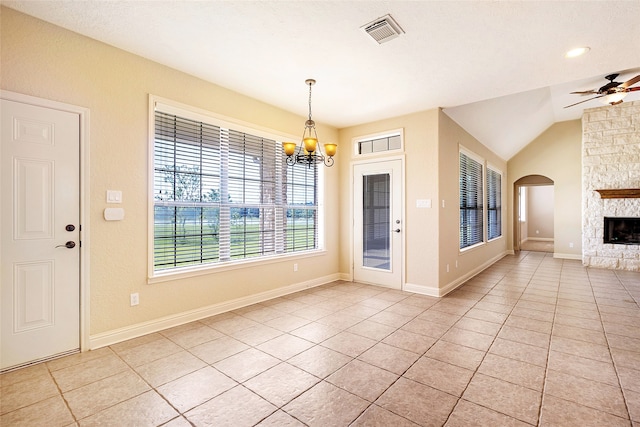 unfurnished dining area featuring a fireplace, arched walkways, ceiling fan with notable chandelier, light tile patterned floors, and visible vents