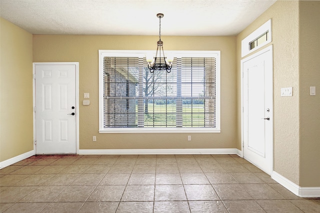 tiled foyer featuring baseboards, a textured ceiling, a textured wall, and a chandelier