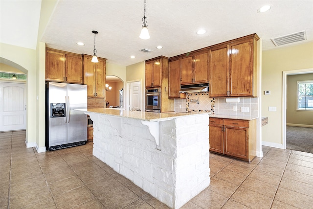 kitchen with stainless steel fridge with ice dispenser, under cabinet range hood, arched walkways, and visible vents