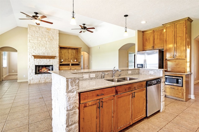 kitchen with a sink, open floor plan, a ceiling fan, appliances with stainless steel finishes, and light tile patterned floors