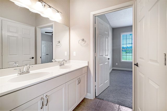 bathroom featuring a sink, baseboards, tile patterned flooring, and double vanity