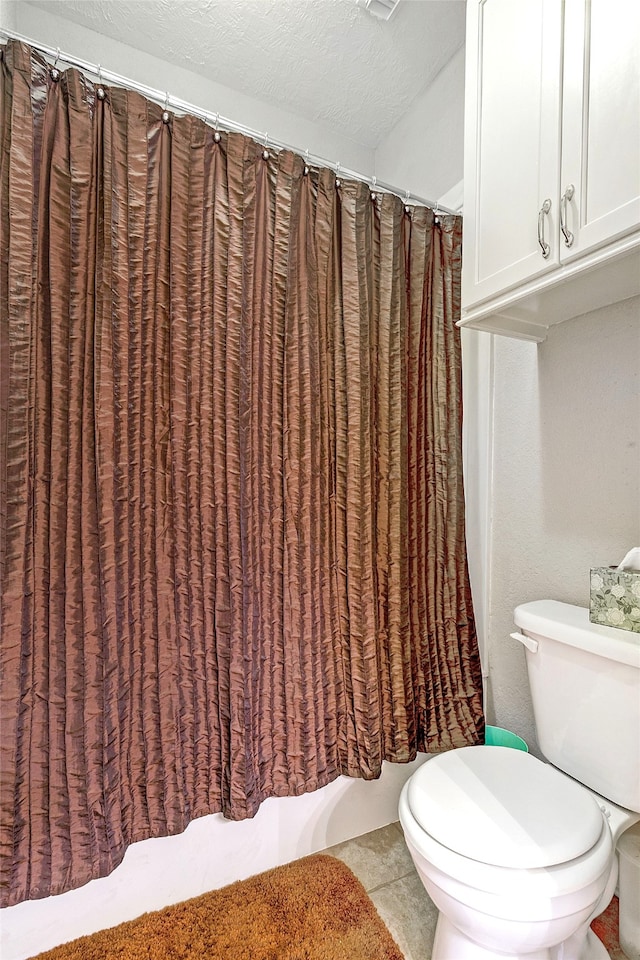 bathroom featuring tile patterned flooring, curtained shower, and toilet