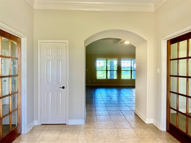 corridor with arched walkways, ornamental molding, and baseboards
