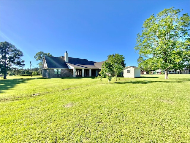 rear view of house featuring an outbuilding, a yard, a storage shed, and a chimney