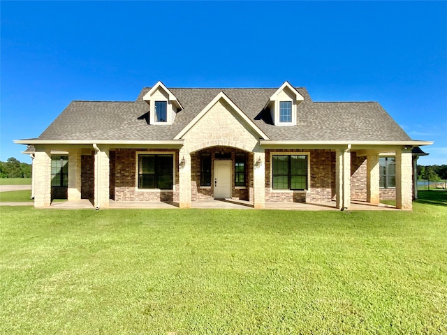 view of front of property with brick siding, a front lawn, roof with shingles, and stone siding