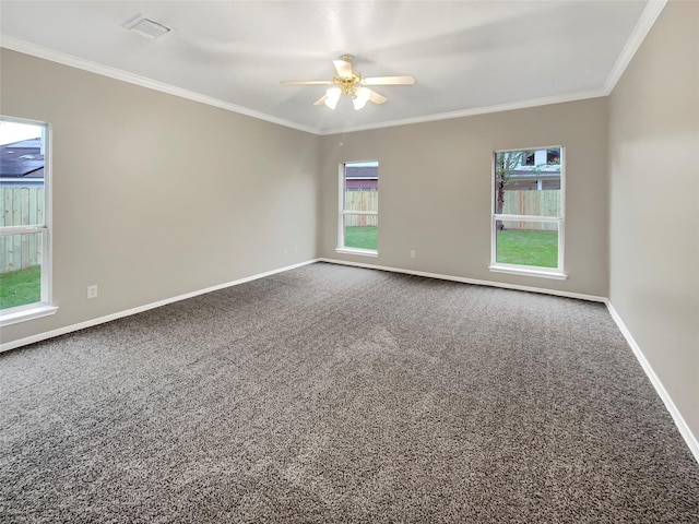 carpeted spare room featuring baseboards, ornamental molding, ceiling fan, and a healthy amount of sunlight