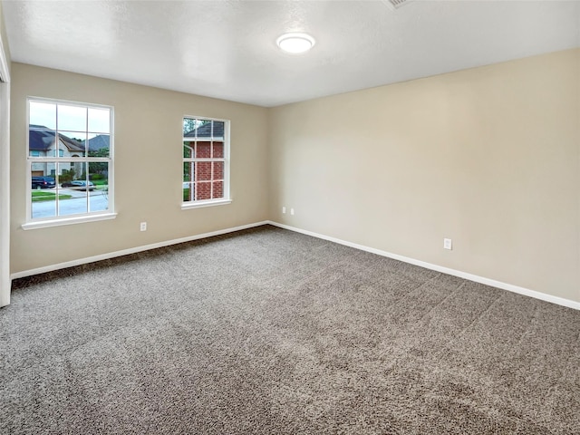 empty room with baseboards and dark colored carpet