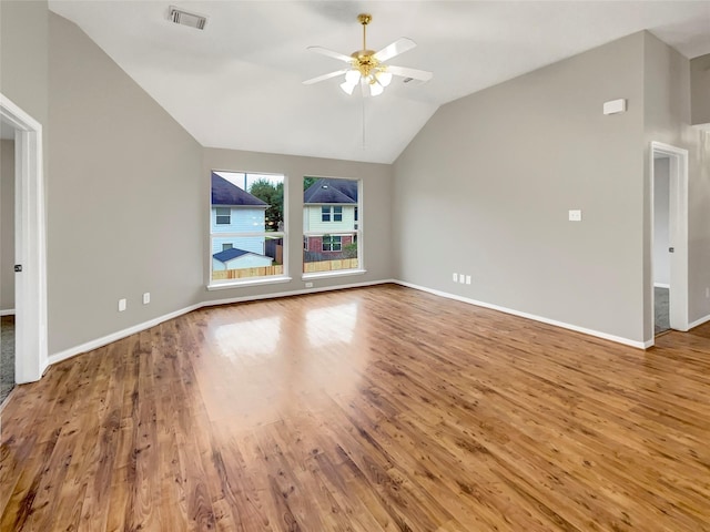 interior space with visible vents, wood finished floors, baseboards, a ceiling fan, and vaulted ceiling